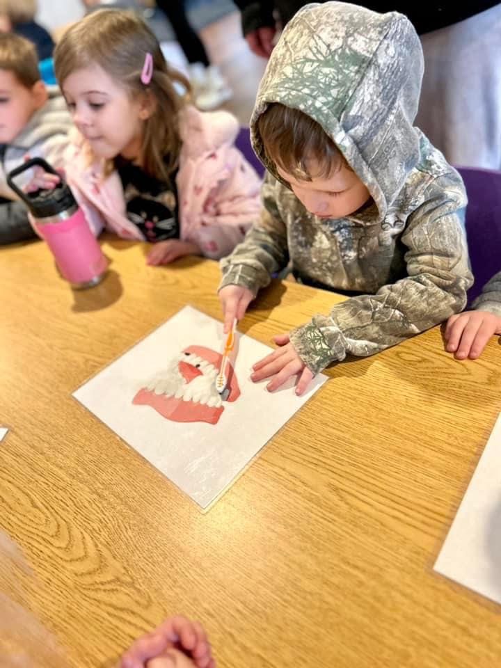 Child practicing brushing on a teeth worksheet during a dental health lesson